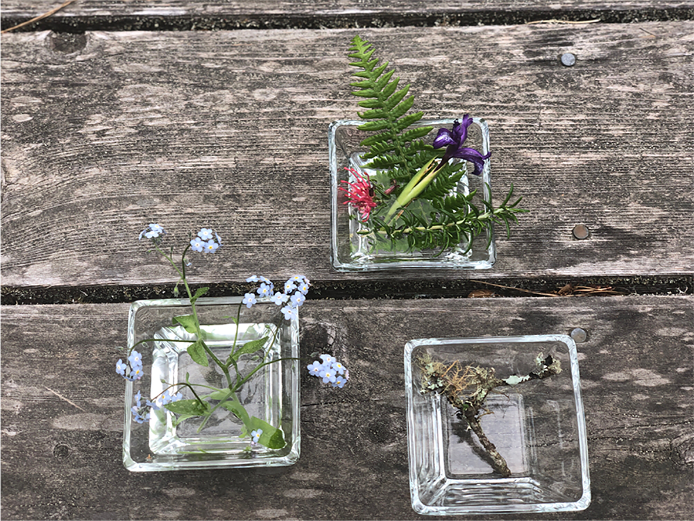Picture of flowers in water on a wooden table. 